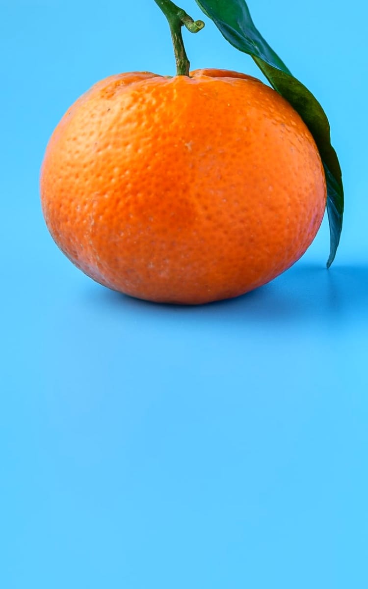 orange with a green leaf on a blue surface